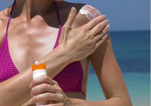 Kobieta nakłada krem z filtrem przeciwsłonecznym