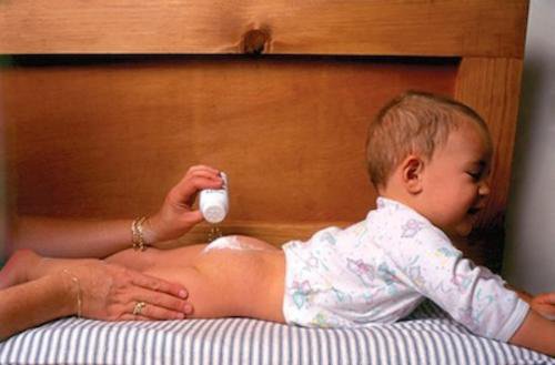 Budzenie dziecka na zmianę pieluchy - mama posypująca malucha talkiem
