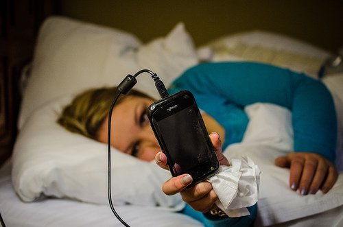 Kobieta w łóżku z telefonem w ręku
