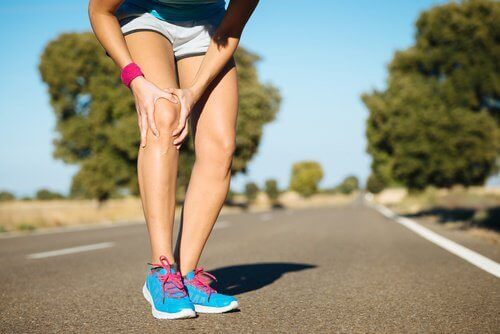 Biegaczka schyla się z powodu bólu kolana