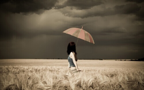 Kobieta z parasolem w polu.