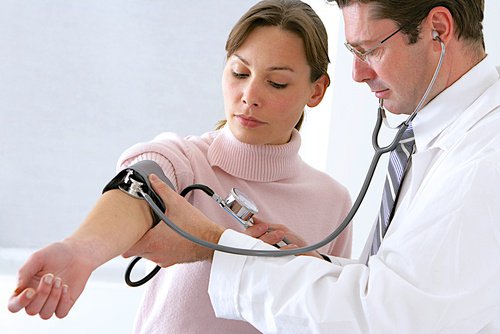 Lekarz bada pacjentce ciśnienie krwi