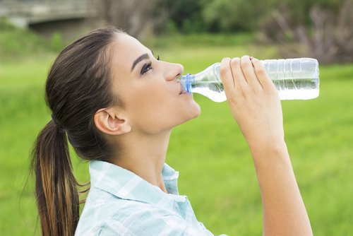 Kobieta pije wodę, by zwalczyć kamienie nerkowe