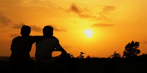 Przyjaciel obejmuje przyjaciela o zachodzie słońca