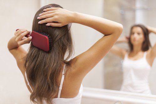 kobieta szczotkuje włosy przed lustrem