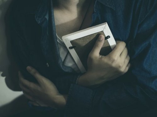 Kobieta ściska ramkę ze zdjęciem - wspomnienia