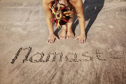 Kobieta uprawia jogę na plaży - namaste