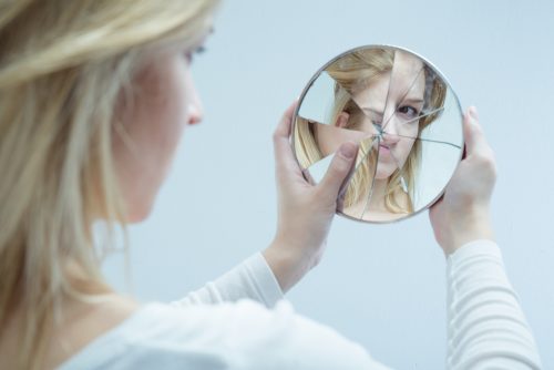 Kobieta patrzy w potłuczone lustro