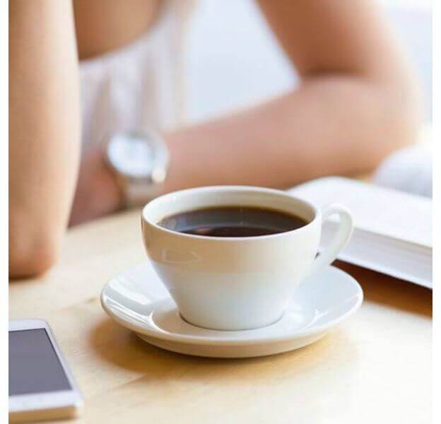 Picie kawy na pusty żołądek to zły pomysł - filiżanka kawy i kobieta