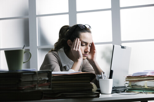 Kobieta w biurze cierpi na ból głowy spowodowany przes stres