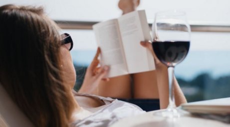 Kobieta czyta książkę przy kieliszku wina