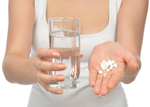 szklanka wody i tabletki na dłoni