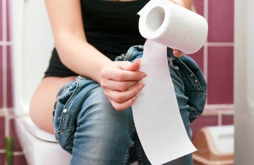 hemoroidy, kobieta siedzi na muszli klozetowej