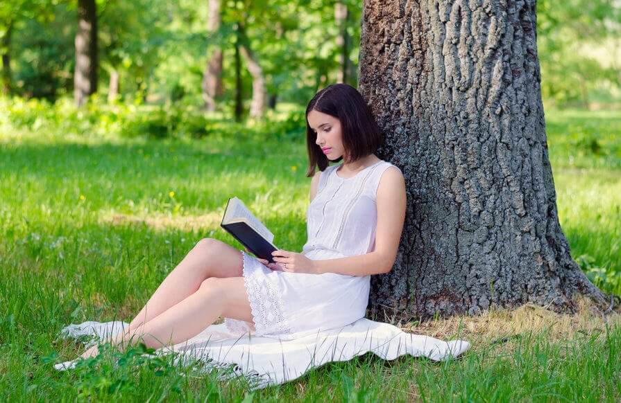 Czytanie książki pod drzewem kobieta