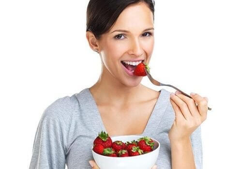 kobieta jedząca truskawki, które zawierają witaminę C
