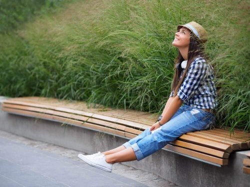 Śmiej się, aby przyciągnąć pozytywną energię. Kobieta siedzi uśmiechnięta na ławce