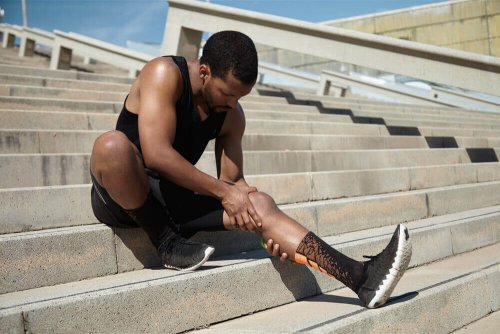 sportowiec na schodach rozciąga mięśnie, ucisk łydki skurcz