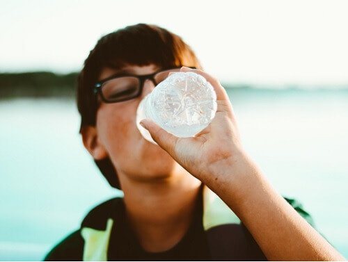 Odwodnienie - chłopiec pije wodę z butelki