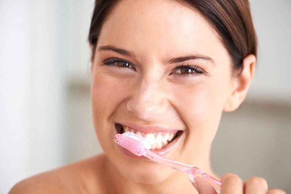 Kobieta szczotkuje zęby, by nie wdała się próchnica