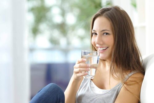 Uśmiechnięta kobieta ze szklanką wody