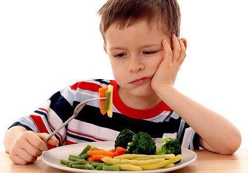Chłopiec patrzący na warzywa z niechecią.