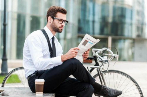 Mężczyzna siedzi przy kawie i gazecie