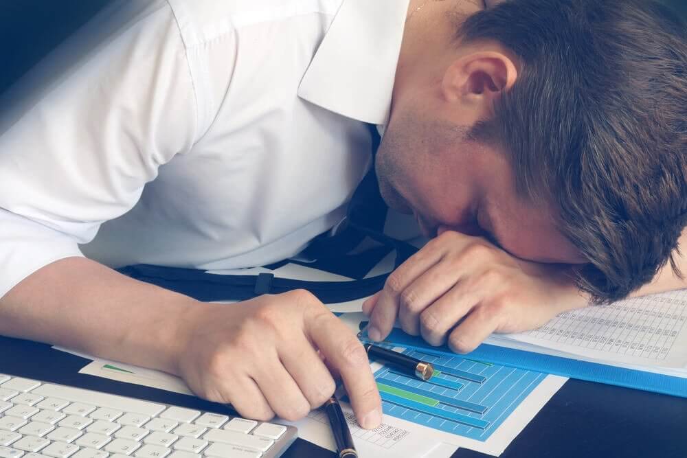 Mężczyzna śpi na dokumentach - zespół chronicznego zmęczenia