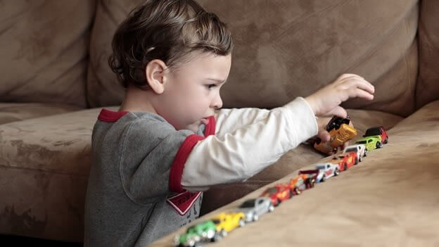 Dziecko z autyzmem układa zabawki w linii prostej