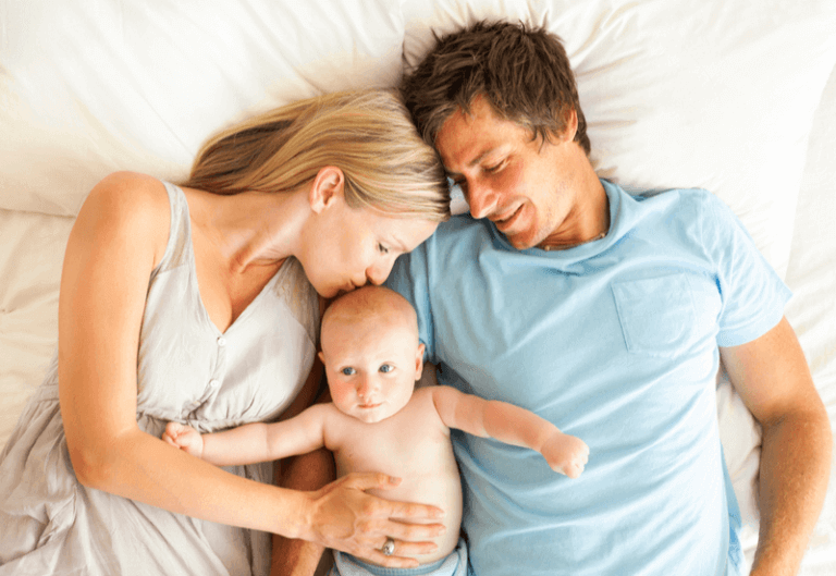Mama, tata i dziecko leżą na łóżku