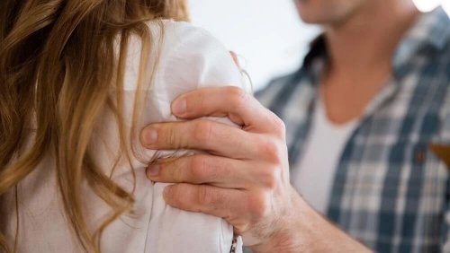 Mężczyzna trzyma kobietę za ramię