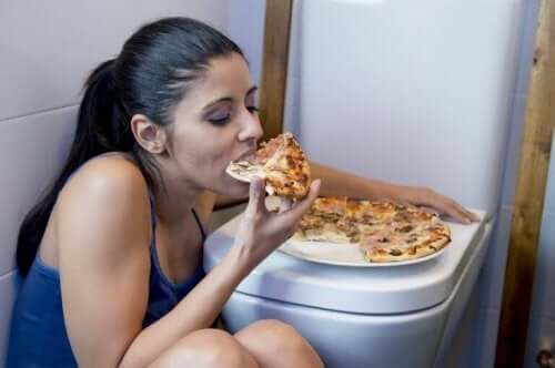 Kobieta je pizzę w łazience