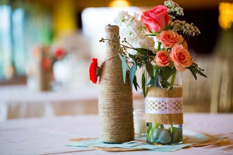 Butelki z kwiatami jako dekoracje pośrodku stołu