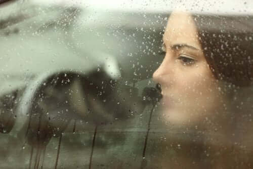 Smutna kobieta patrzy przez okno podczas deszczu