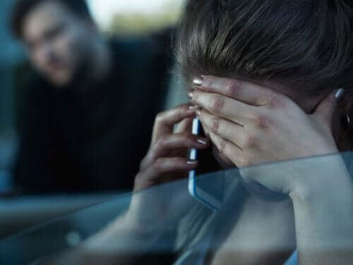 Załamana kobieta rozmawia przez telefon - zgłoszenie przemocy w rodzinie
