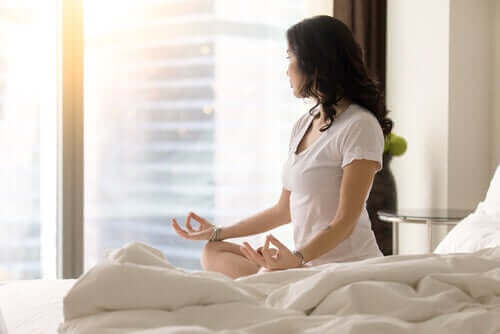Kobieta medytująca na łóżku - jak wyrobić w sobie nawyk?