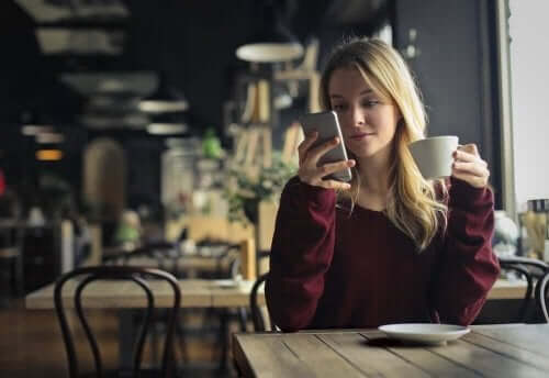 Kobieta pijąca kawę i patrząca na telefon