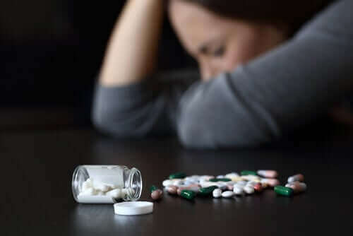 Kobieta śpiąca na stole z rozsypanym tabletkami - senność wywoływana przyjmowaniem leków