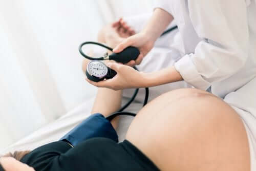 Lekarz mierzący ciśnienie kobiecie w ciąży - co może wywołać przedterminowy poród?