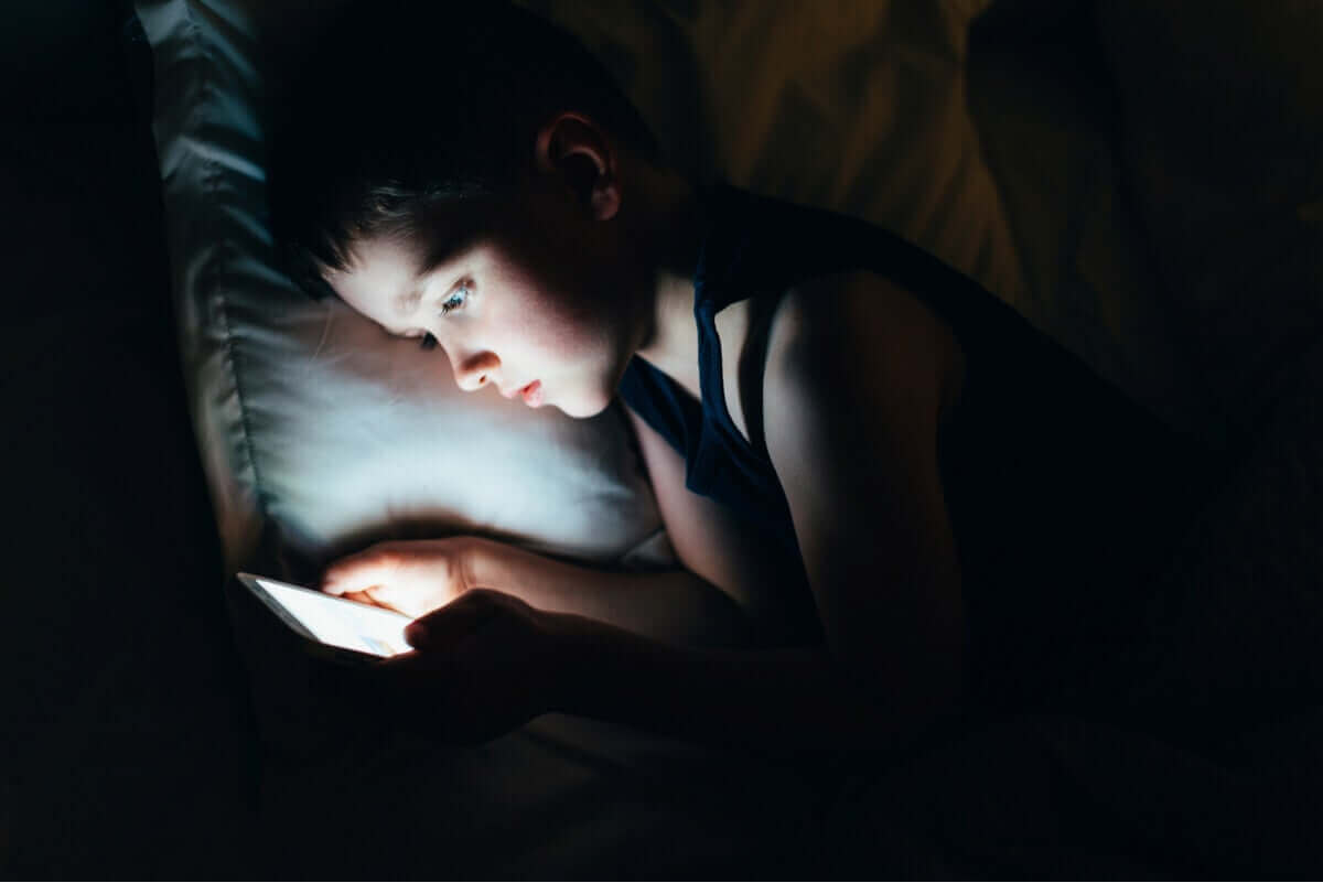 Chłopiec korzystający z telefonu w łóżku