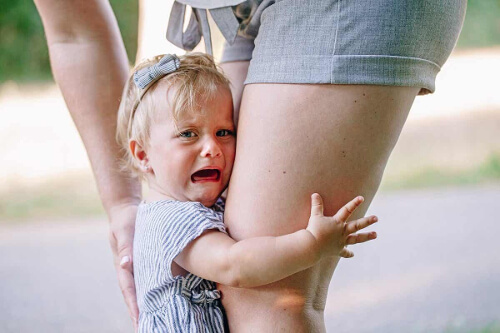 Dziecko trzymające się nogi matki